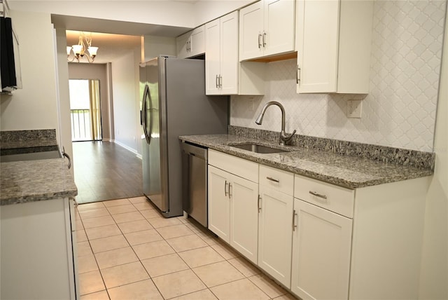 2800 Cove Cay Dr Unit 5D, Clearwater, FL 33760 - kitchen featuring white cabinets, tasteful backsplash, stainless steel appliances, light tile patterned flooring, and a chandelier