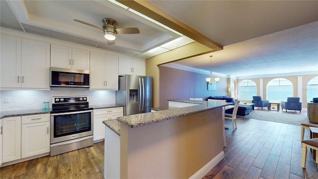 4950 Gulf Blvd Unit 1006, St Pete Beach, FL 33706 - kitchen with stainless steel appliances, a tray ceiling, backsplash, and dark wood finished floors