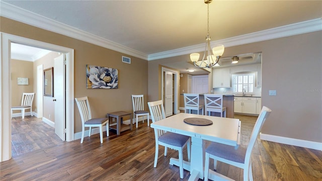 4950 Gulf Blvd Unit 1006, St Pete Beach, FL 33706 - dining space with ornamental molding, a chandelier, and dark wood finished floors