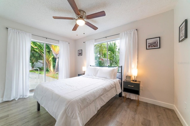 574 6th Ave SE, Largo, FL 33771 - bedroom featuring access to exterior, multiple windows, wood finished floors, a textured ceiling, and ceiling fan