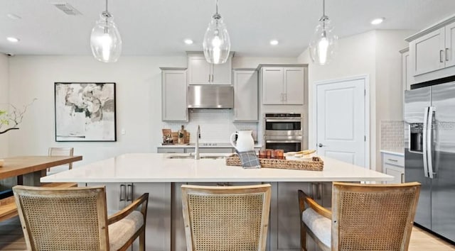 2422 Babbling Brook Blvd, Auburndale, FL 33823 - kitchen with stainless steel appliances, under cabinet range hood, gray cabinetry, tasteful backsplash, and recessed lighting