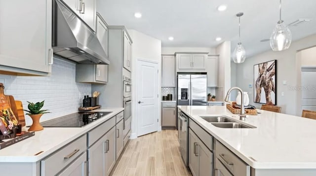 2422 Babbling Brook Blvd, Auburndale, FL 33823 - kitchen featuring under cabinet range hood, gray cabinets, appliances with stainless steel finishes, a center island with sink, and decorative backsplash
