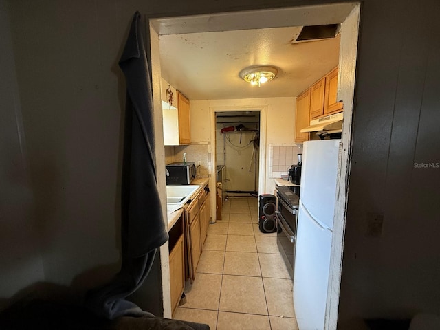 13097 120th St, Largo, FL 33778 - kitchen with freestanding refrigerator, light tile patterned floors, under cabinet range hood, light countertops, and range with two ovens