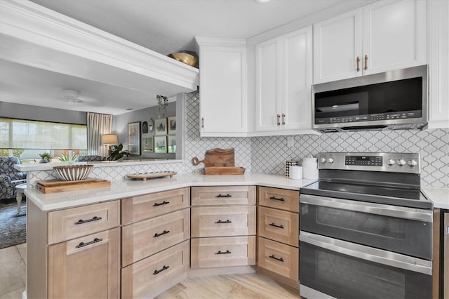 2009 Woodward Ave, Dunedin, FL 34698 - kitchen with appliances with stainless steel finishes, a peninsula, backsplash, and light countertops
