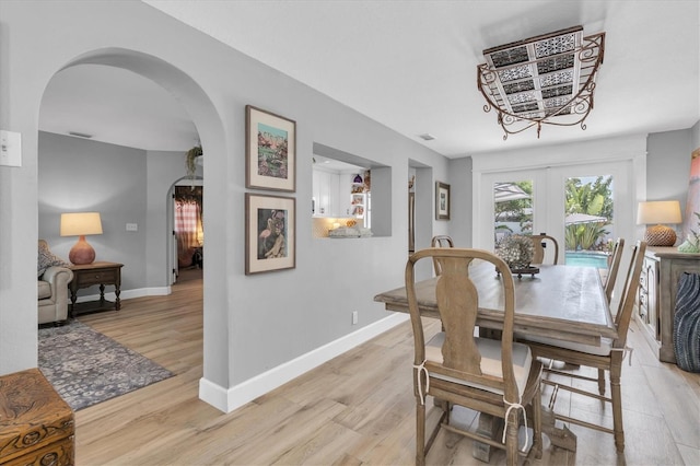 2009 Woodward Ave, Dunedin, FL 34698 - dining room featuring arched walkways, light wood-style flooring, and french doors