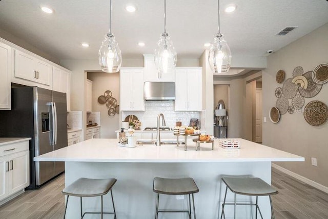 2257 Cypress Creek St, Auburndale, FL 33823 - kitchen with stainless steel refrigerator with ice dispenser, exhaust hood, a breakfast bar, light wood-style floors, and recessed lighting