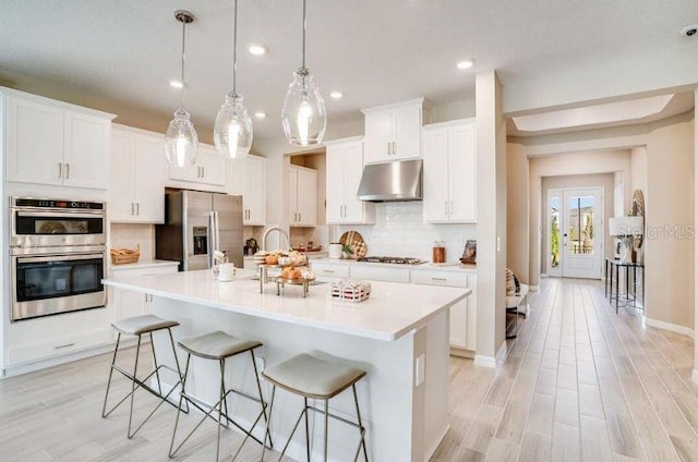 2257 Cypress Creek St, Auburndale, FL 33823 - kitchen featuring appliances with stainless steel finishes, under cabinet range hood, a breakfast bar area, decorative backsplash, and light countertops