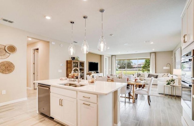 2257 Cypress Creek St, Auburndale, FL 33823 - kitchen featuring appliances with stainless steel finishes, open floor plan, white cabinets, light countertops, and a kitchen island with sink
