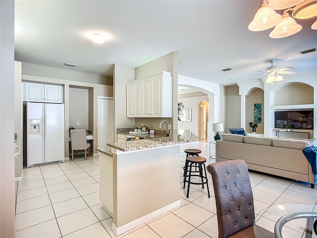 9803 Ocasta St, Riverview, FL 33569 - kitchen featuring white fridge with ice dispenser, arched walkways, a peninsula, light stone countertops, and a breakfast bar