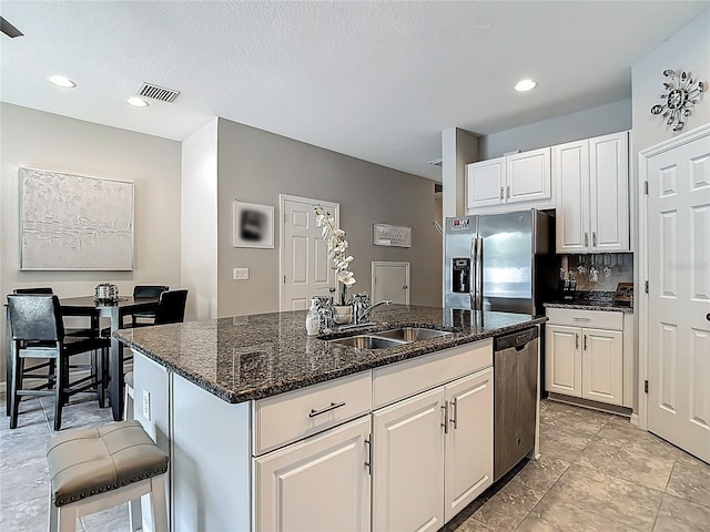 7133 Summer Holly Pl, Riverview, FL 33578 - kitchen with stainless steel appliances, white cabinetry, a kitchen island with sink, dark stone counters, and recessed lighting