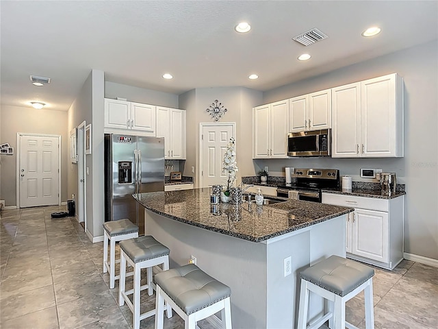 7133 Summer Holly Pl, Riverview, FL 33578 - kitchen featuring appliances with stainless steel finishes, a kitchen breakfast bar, white cabinetry, dark stone counters, and recessed lighting