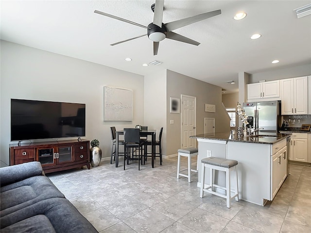 7133 Summer Holly Pl, Riverview, FL 33578 - kitchen with stainless steel refrigerator with ice dispenser, open floor plan, a ceiling fan, a kitchen bar, and a kitchen island