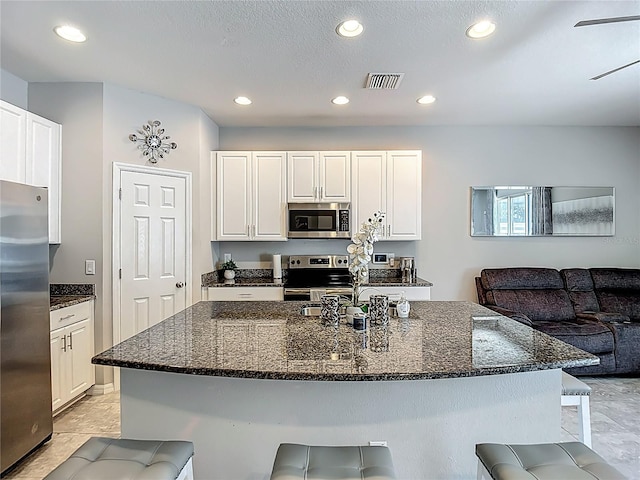 7133 Summer Holly Pl, Riverview, FL 33578 - kitchen with stainless steel appliances, recessed lighting, a kitchen breakfast bar, dark stone counters, and white cabinets
