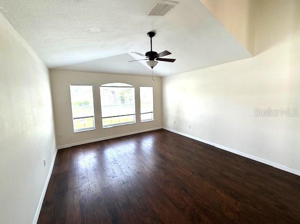 24838 Oakhaven Ct, Lutz, FL 33559 - spare room featuring dark wood finished floors, a ceiling fan, vaulted ceiling, and a textured ceiling