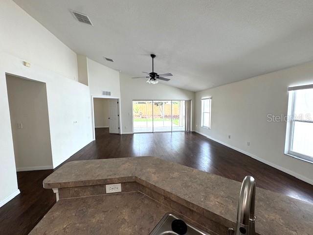 24838 Oakhaven Ct, Lutz, FL 33559 - unfurnished living room featuring vaulted ceiling, dark wood-style floors, and ceiling fan