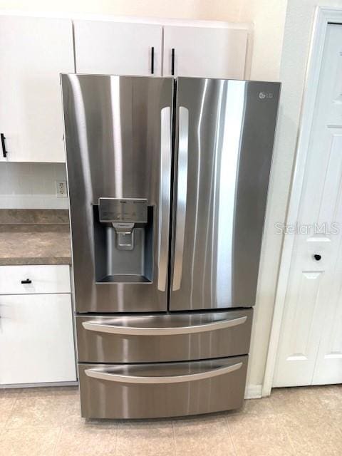 24838 Oakhaven Ct, Lutz, FL 33559 - detailed view of stainless steel refrigerator with ice dispenser, dark countertops, and white cabinets