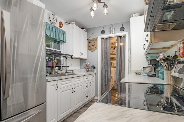 4530 David Dr, Bartow, FL 33830 - kitchen with freestanding refrigerator, ventilation hood, range with electric cooktop, white cabinetry, and wood finished floors