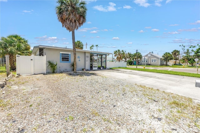 360 71st Ave, St Pete Beach, FL 33706 - view of front facade with stucco siding, concrete driveway, a gate, and a residential view