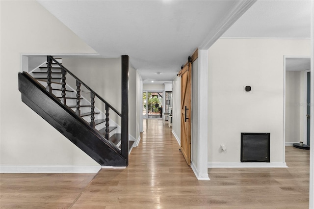 entryway with a barn door, stairs, and light wood-type flooring