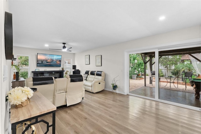 living room featuring light wood finished floors, recessed lighting, a ceiling fan, and a fireplace