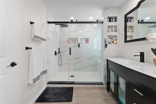 full bathroom with a marble finish shower, vanity, and wood finished floors