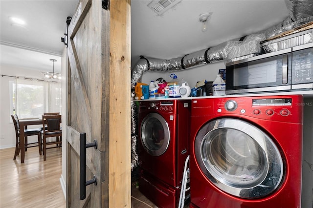 washroom featuring separate washer and dryer, a barn door, and wood finished floors