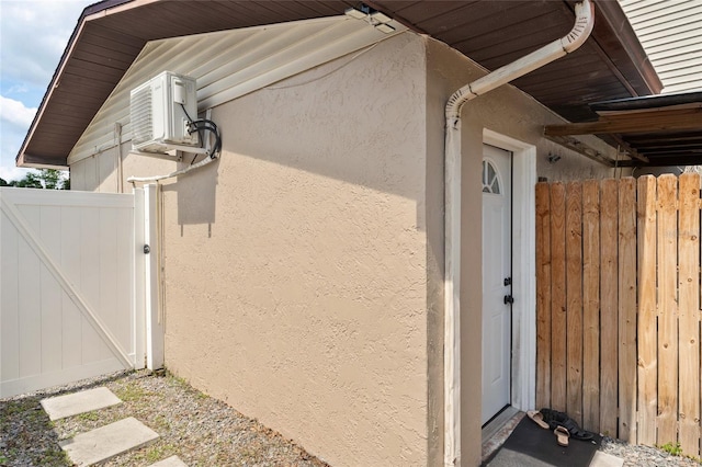 view of side of home with stucco siding and a gate