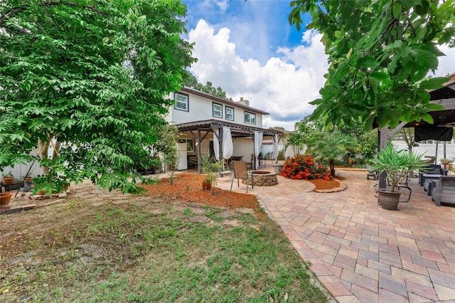 rear view of house featuring an outdoor fire pit, a patio area, and a chimney