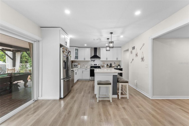 kitchen with light wood-style floors, recessed lighting, appliances with stainless steel finishes, a breakfast bar area, and light countertops