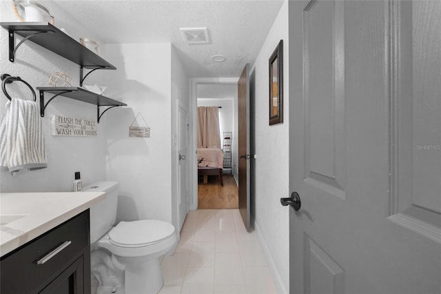 bathroom featuring vanity, a textured ceiling, tile patterned floors, and ensuite bathroom