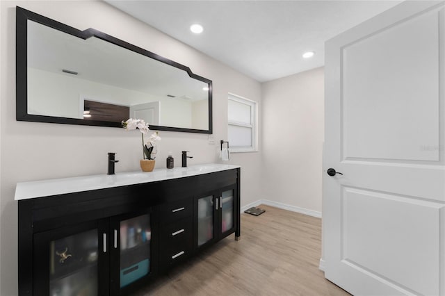 bathroom featuring double vanity, wood finished floors, and recessed lighting