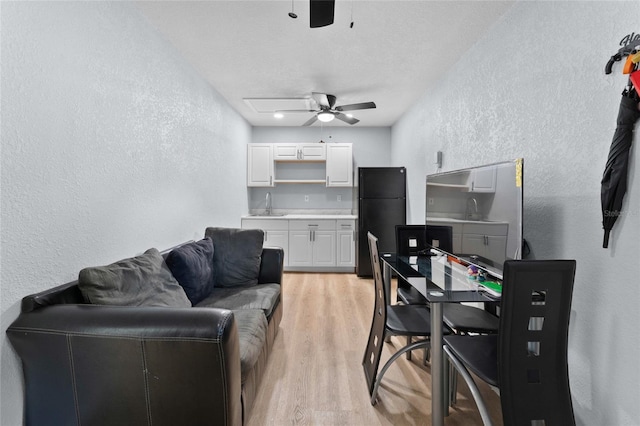 living room featuring a textured wall, ceiling fan, and light wood-type flooring