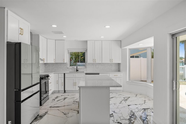 600 115th Ave, Treasure Island, FL 33706 - kitchen featuring freestanding refrigerator, range, backsplash, light marble finish flooring, and white cabinetry