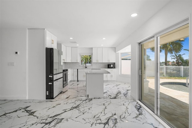 600 115th Ave, Treasure Island, FL 33706 - kitchen featuring freestanding refrigerator, recessed lighting, light marble finish floors, a kitchen island, and white cabinetry
