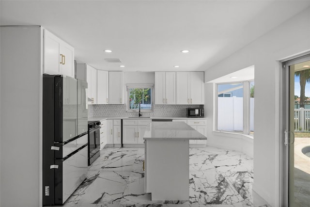 600 115th Ave, Treasure Island, FL 33706 - kitchen with freestanding refrigerator, black microwave, stove, white cabinetry, and recessed lighting