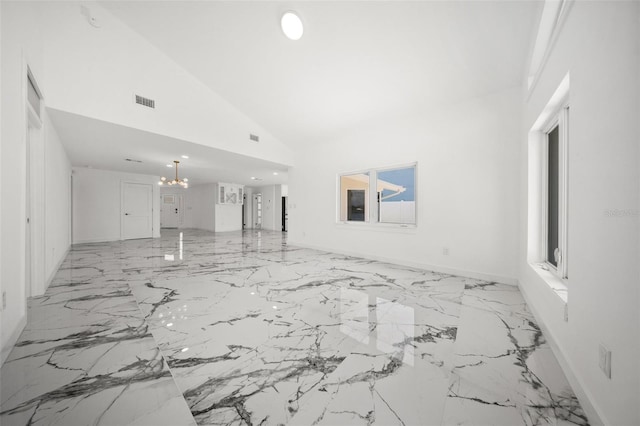 600 115th Ave, Treasure Island, FL 33706 - unfurnished living room with a chandelier, light marble finish flooring, and high vaulted ceiling