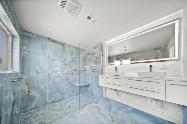 600 115th Ave, Treasure Island, FL 33706 - full bathroom with a marble finish shower, double vanity, marble look tile flooring, and tile walls