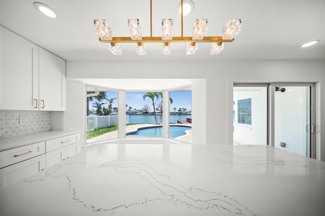 600 115th Ave, Treasure Island, FL 33706 - kitchen featuring a water view, white cabinetry, decorative backsplash, light stone countertops, and recessed lighting
