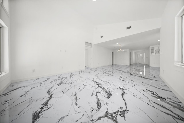 600 115th Ave, Treasure Island, FL 33706 - unfurnished living room featuring a chandelier, a high ceiling, and marble finish flooring