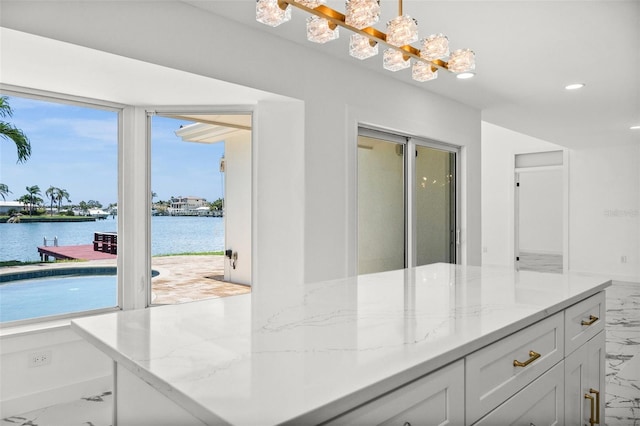 600 115th Ave, Treasure Island, FL 33706 - kitchen with marble finish floors, light stone countertops, white cabinets, a water view, and recessed lighting