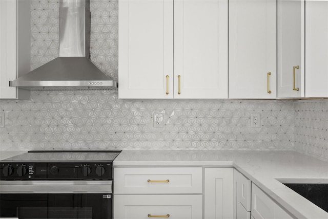 600 115th Ave, Treasure Island, FL 33706 - kitchen with wall chimney range hood, range, white cabinetry, and decorative backsplash