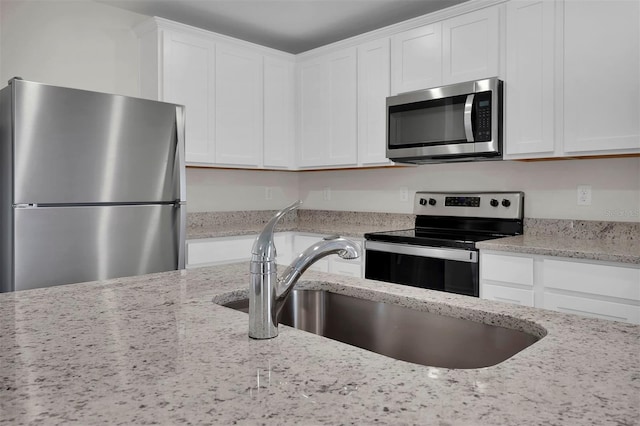 7504 SW 128th St, Ocala, FL 34473 - kitchen featuring appliances with stainless steel finishes, white cabinets, and light stone countertops