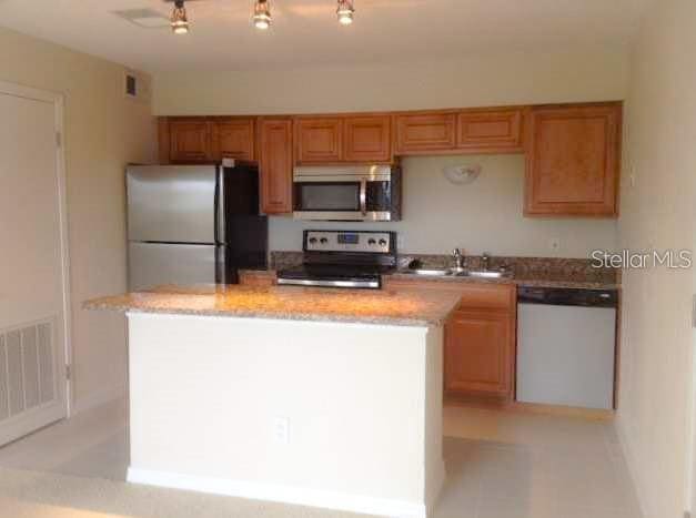 kitchen with light stone counters, sink, a kitchen island, and appliances with stainless steel finishes