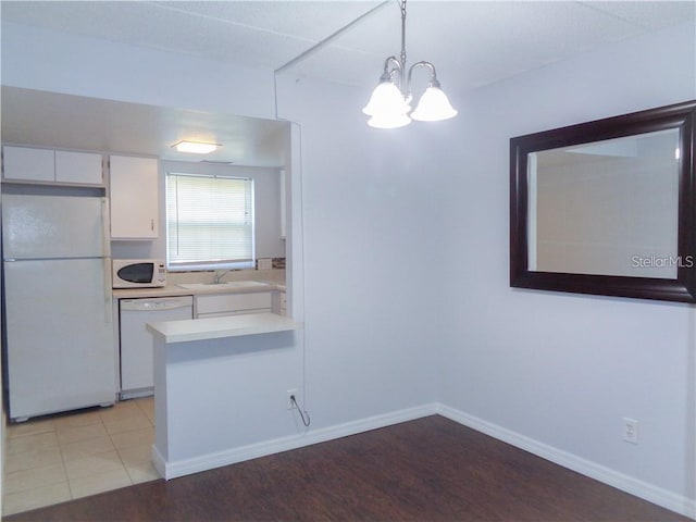 kitchen with decorative light fixtures, white cabinetry, sink, kitchen peninsula, and white appliances