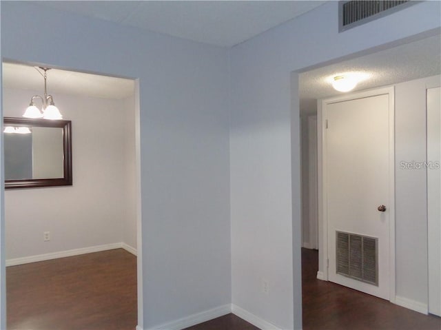 empty room featuring dark hardwood / wood-style flooring and an inviting chandelier