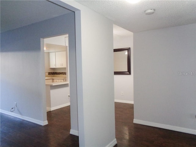 hallway with a textured ceiling and dark hardwood / wood-style flooring