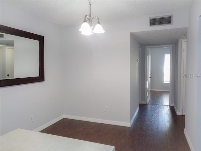 unfurnished dining area featuring an inviting chandelier and dark hardwood / wood-style flooring