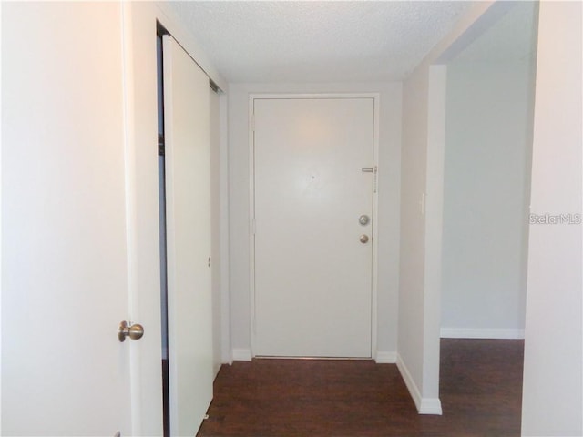 hallway featuring dark wood-type flooring and a textured ceiling