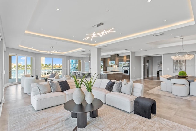 living room with a tray ceiling and a notable chandelier