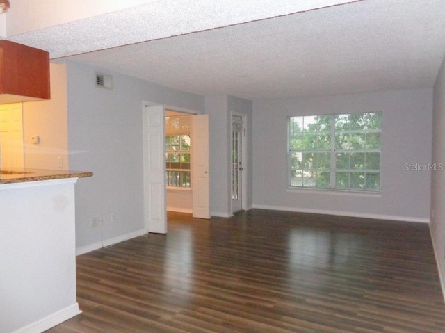 unfurnished living room featuring a textured ceiling and dark wood-type flooring